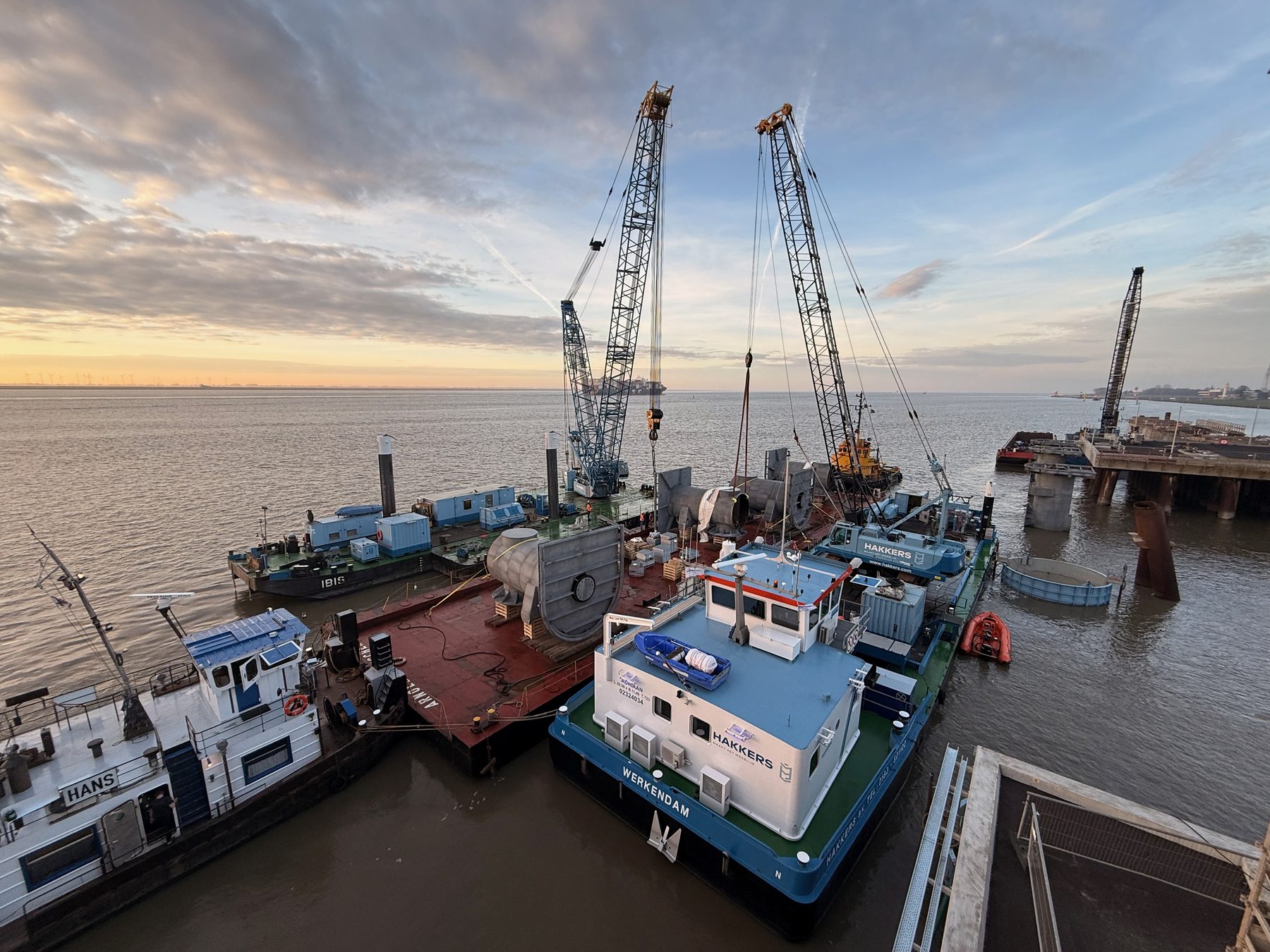 Marine jetty under construction at dusk with crawler cranes